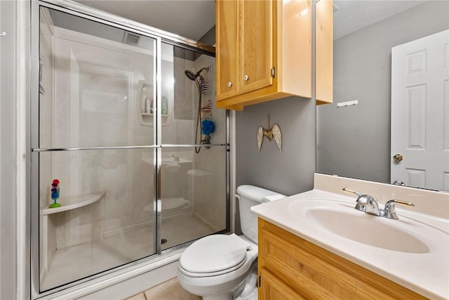 bathroom featuring vanity, toilet, a stall shower, and tile patterned floors