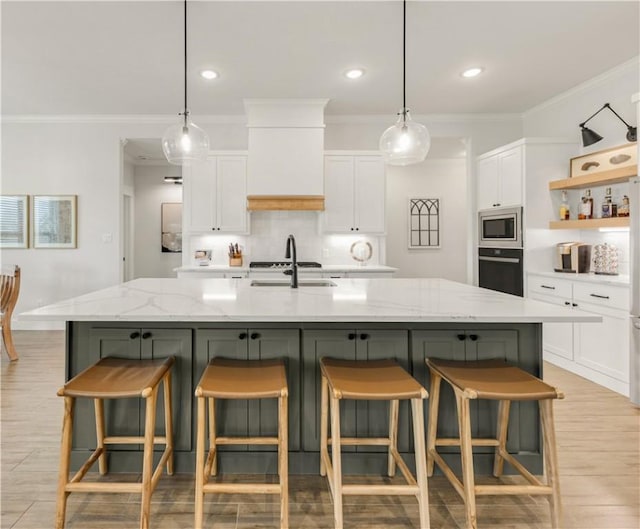 kitchen featuring wall oven, stainless steel microwave, white cabinetry, and a sink