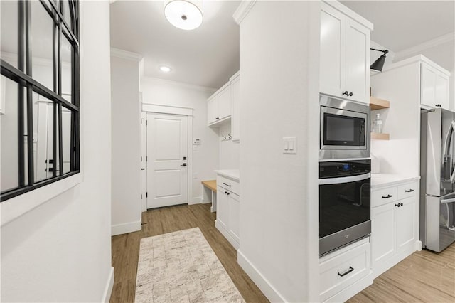 kitchen with open shelves, appliances with stainless steel finishes, white cabinets, crown molding, and light countertops