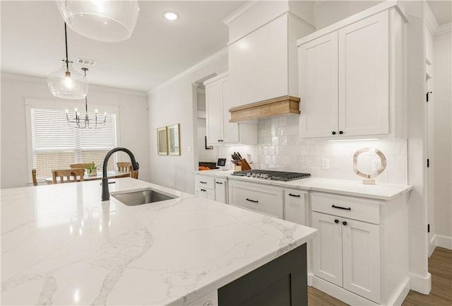 kitchen featuring visible vents, crown molding, decorative backsplash, stainless steel gas stovetop, and a sink