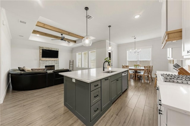 kitchen featuring visible vents, light wood-style flooring, a fireplace, gray cabinets, and a sink