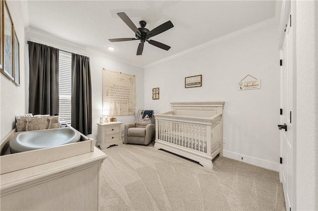 bedroom with light colored carpet, baseboards, crown molding, and a nursery area