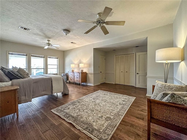 bedroom featuring ceiling fan, dark hardwood / wood-style flooring, and a textured ceiling