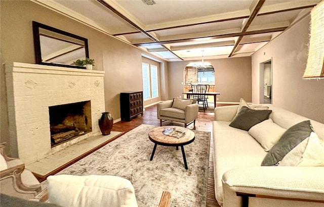 living room with beam ceiling, hardwood / wood-style flooring, a brick fireplace, and coffered ceiling