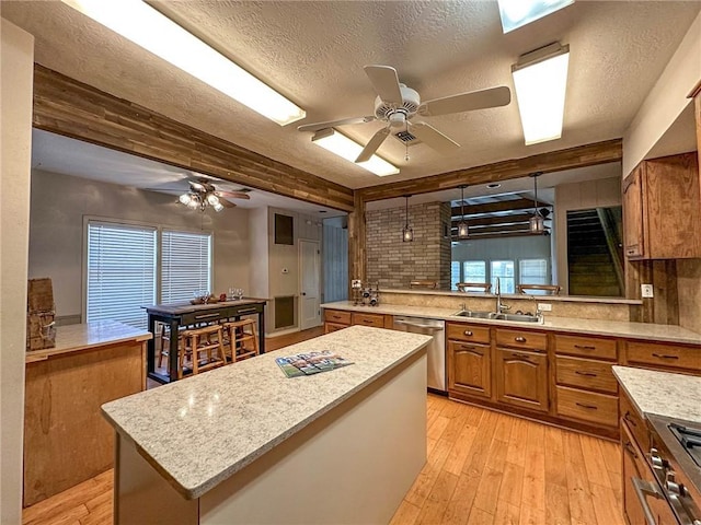 kitchen featuring sink, stainless steel dishwasher, light hardwood / wood-style floors, a textured ceiling, and a kitchen island