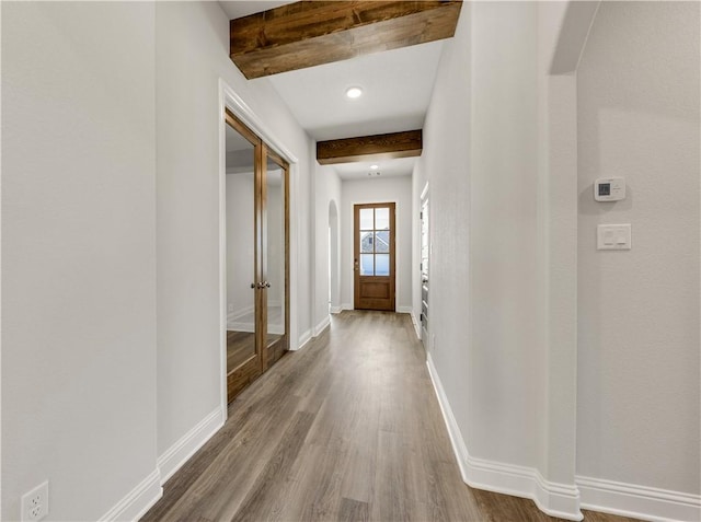 corridor with beam ceiling and hardwood / wood-style flooring