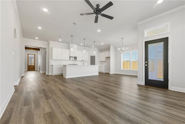 unfurnished living room with crown molding, dark wood-type flooring, and ceiling fan with notable chandelier