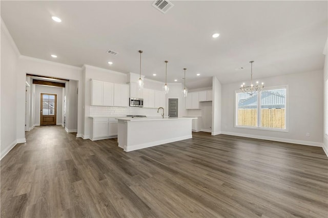 kitchen with white cabinetry, hanging light fixtures, dark wood-type flooring, and an island with sink