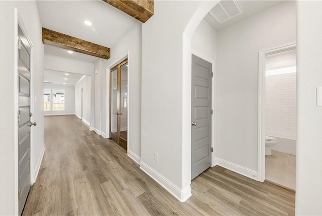 hall featuring beamed ceiling and light wood-type flooring