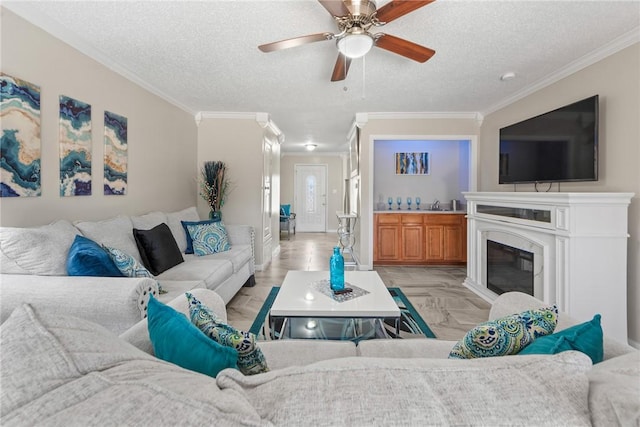 living room with ceiling fan, crown molding, and a textured ceiling