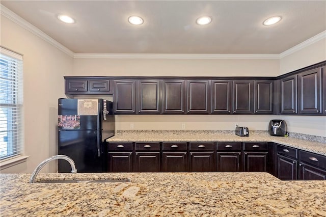 kitchen with black fridge, ornamental molding, sink, and dark brown cabinetry