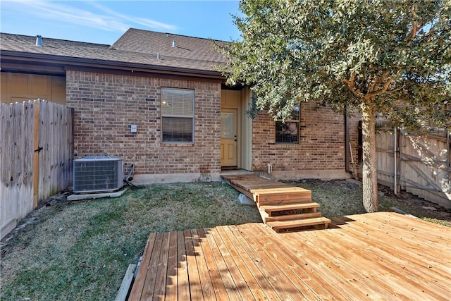 rear view of house with central AC unit, a lawn, and a wooden deck