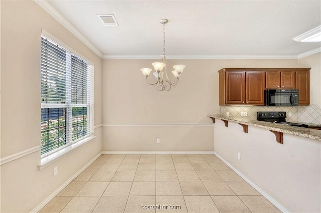 kitchen with pendant lighting, backsplash, black appliances, crown molding, and a kitchen bar