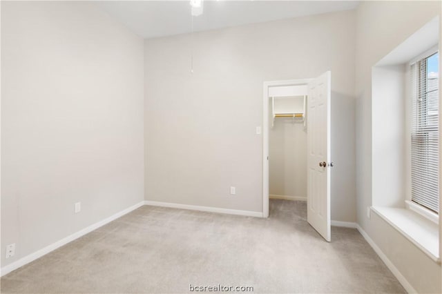 unfurnished bedroom with light carpet, a closet, and a spacious closet