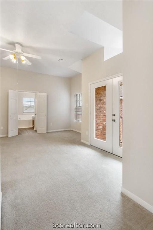 empty room featuring french doors, light colored carpet, ceiling fan, and a healthy amount of sunlight