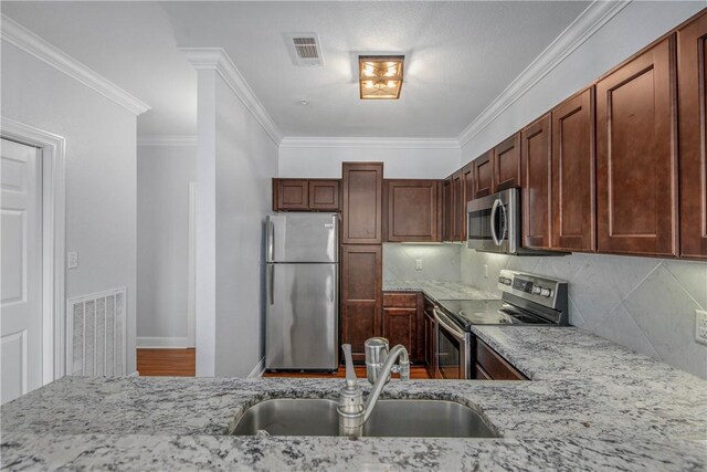 801 Luther St W Unit 106, College Station, TX 77840 - kitchen with stainless steel appliances, light stone countertops, ornamental molding, decorative backsplash, and wood finished floors
