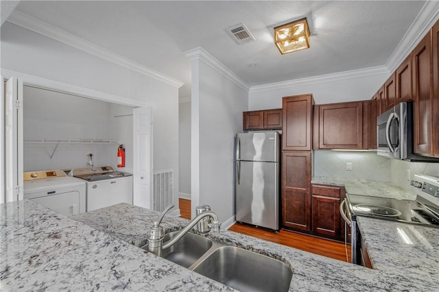 801 Luther St W Unit 106, College Station, TX 77840 - kitchen with stainless steel appliances, washing machine and clothes dryer, wood finished floors, tasteful backsplash, and ornamental molding