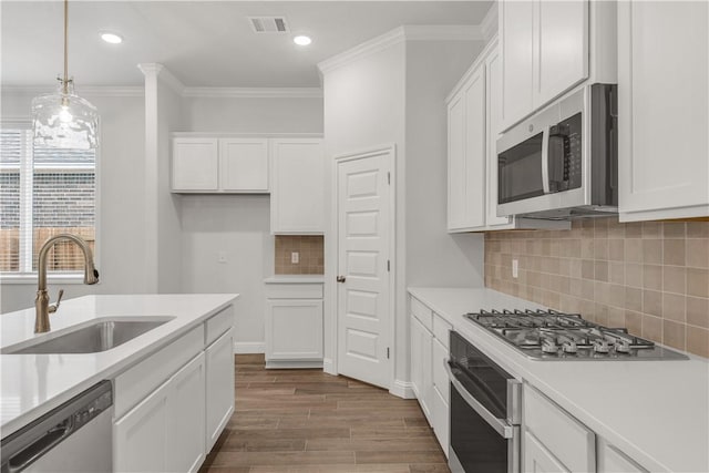 3702 Archer Falls Ct, College Station, TX 77845 - kitchen with stainless steel appliances, white cabinets, dark wood finished floors, crown molding, and light countertops