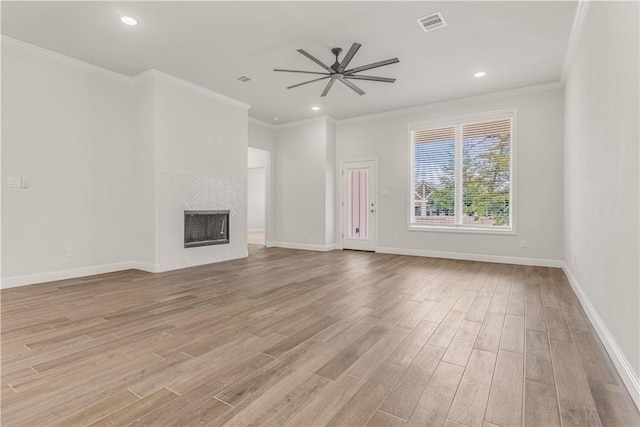 unfurnished living room with light hardwood / wood-style flooring, ceiling fan, ornamental molding, and a tiled fireplace