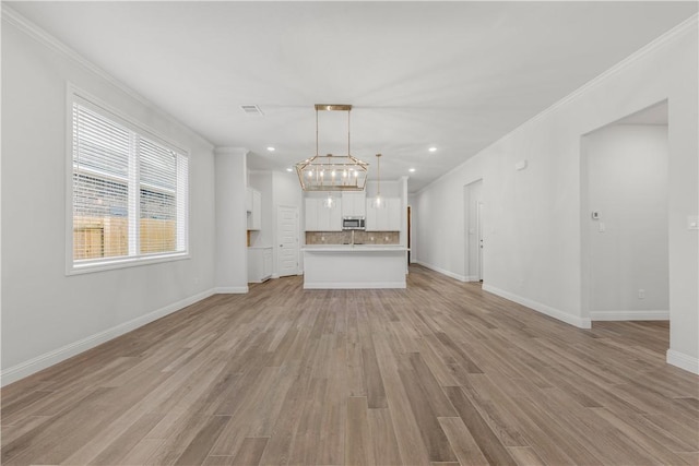 unfurnished living room featuring crown molding, a chandelier, and light wood-type flooring