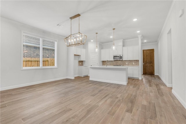 3702 Archer Falls Ct, College Station, TX 77845 - kitchen featuring stainless steel microwave, light wood-style floors, white cabinetry, decorative backsplash, and crown molding