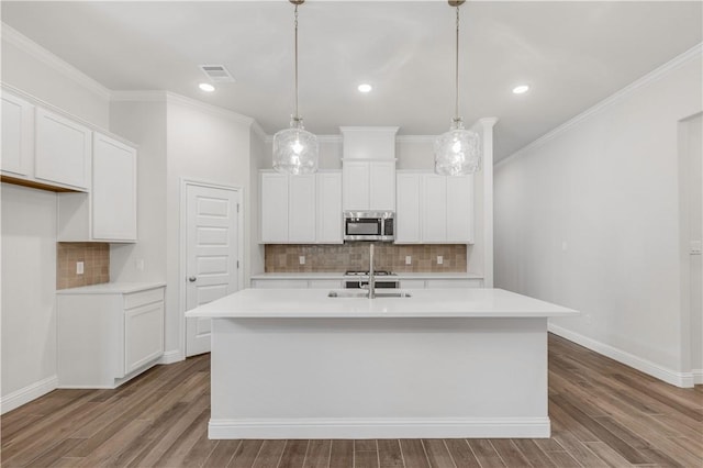 kitchen featuring white cabinets, ornamental molding, an island with sink, and hanging light fixtures