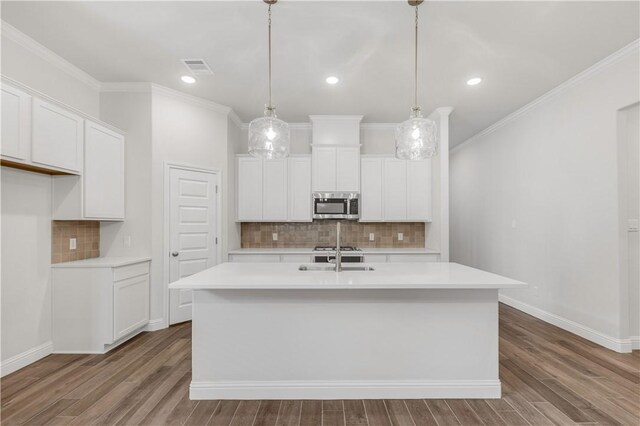 3702 Archer Falls Ct, College Station, TX 77845 - kitchen with stainless steel microwave, tasteful backsplash, a kitchen island with sink, light countertops, and white cabinetry