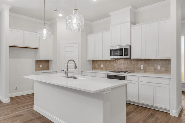 kitchen with stainless steel appliances, white cabinetry, a center island with sink, and sink