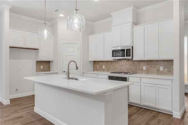 3702 Archer Falls Ct, College Station, TX 77845 - kitchen with appliances with stainless steel finishes, wood finished floors, white cabinets, an island with sink, and crown molding