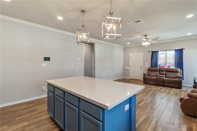 kitchen featuring a center island, blue cabinets, ceiling fan with notable chandelier, and hardwood / wood-style flooring