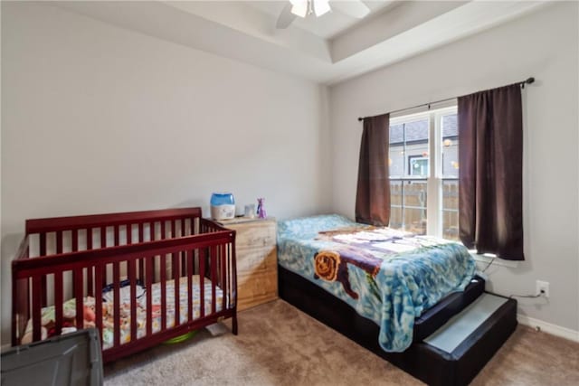 carpeted bedroom with a tray ceiling and ceiling fan