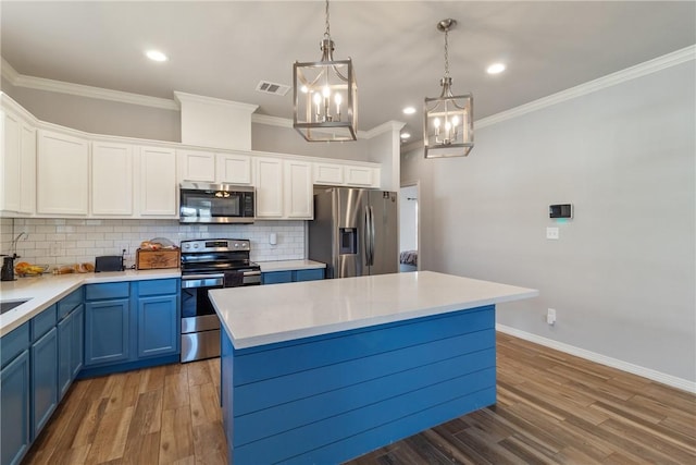 kitchen with appliances with stainless steel finishes, a kitchen island, dark wood-type flooring, blue cabinetry, and white cabinetry