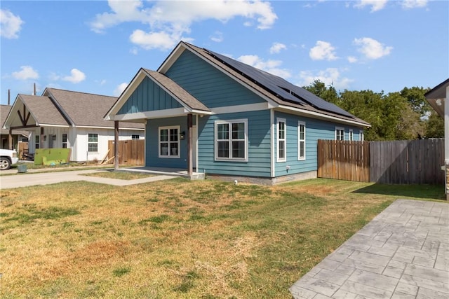 view of front of property featuring a front lawn, covered porch, and solar panels