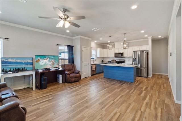 kitchen featuring pendant lighting, light wood-type flooring, blue cabinetry, a kitchen island, and stainless steel appliances