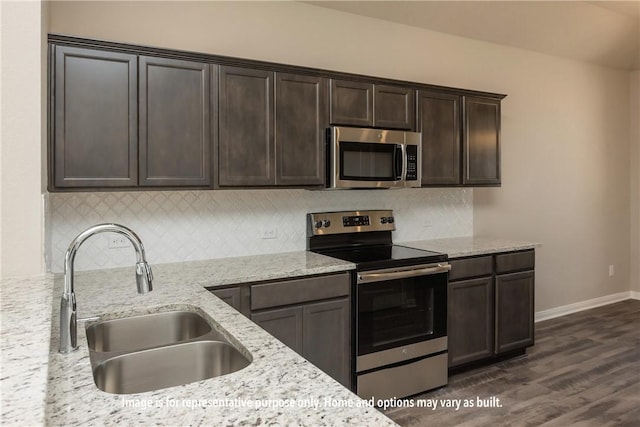 kitchen with light stone countertops, dark hardwood / wood-style flooring, dark brown cabinets, stainless steel appliances, and sink