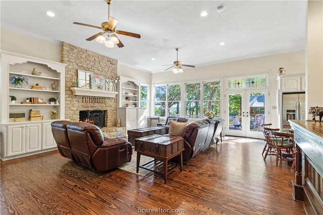 living room featuring french doors, crown molding, dark hardwood / wood-style floors, ceiling fan, and a fireplace