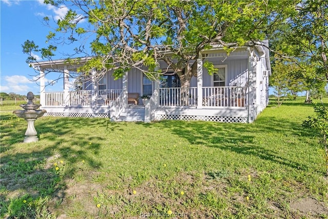 back of house featuring a lawn and covered porch