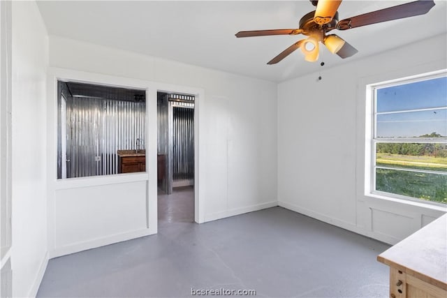 spare room with ceiling fan and concrete floors