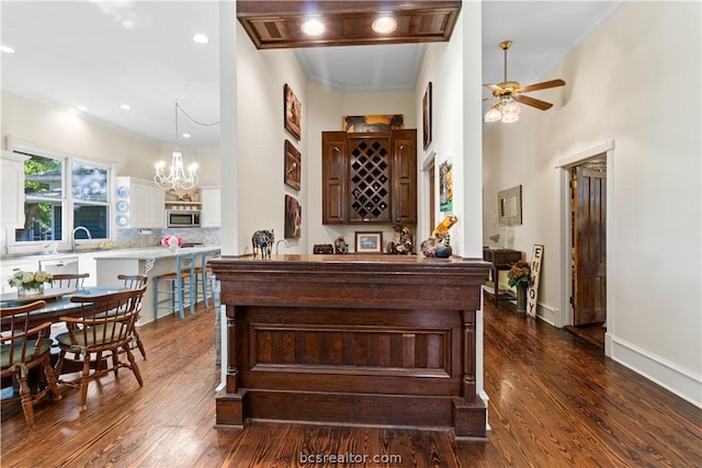 bar with ceiling fan with notable chandelier, sink, dark hardwood / wood-style floors, decorative light fixtures, and white cabinetry