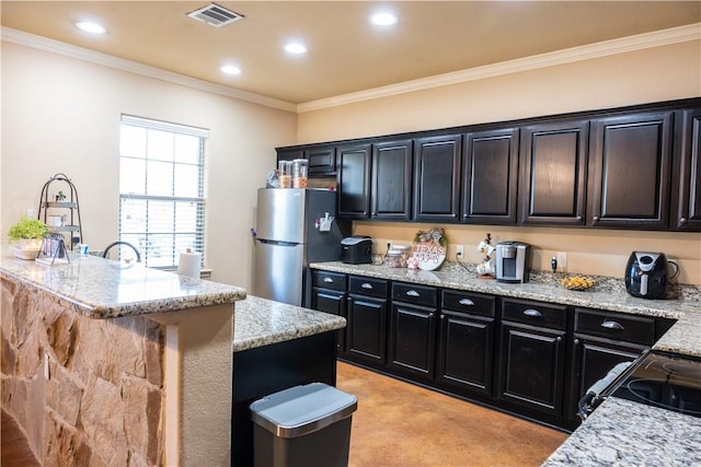 kitchen featuring ornamental molding, a kitchen island with sink, stainless steel fridge, and light stone counters