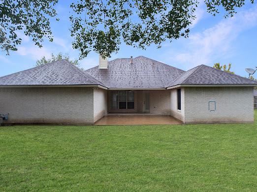 rear view of property featuring a yard and a patio