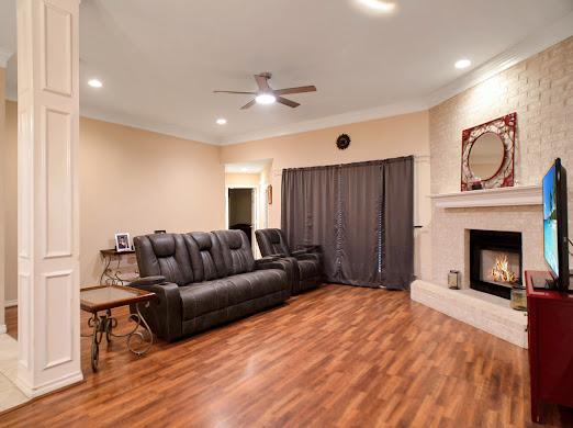 living room with ceiling fan, a large fireplace, wood-type flooring, and crown molding