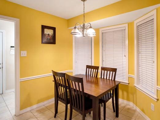 dining space with light tile patterned floors and an inviting chandelier