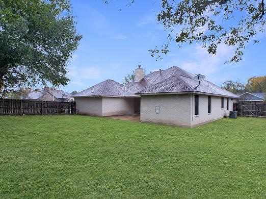 back of house with a lawn and central AC