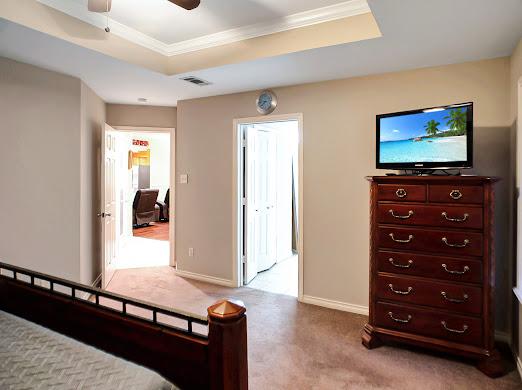 unfurnished bedroom with a raised ceiling, ceiling fan, crown molding, and light carpet