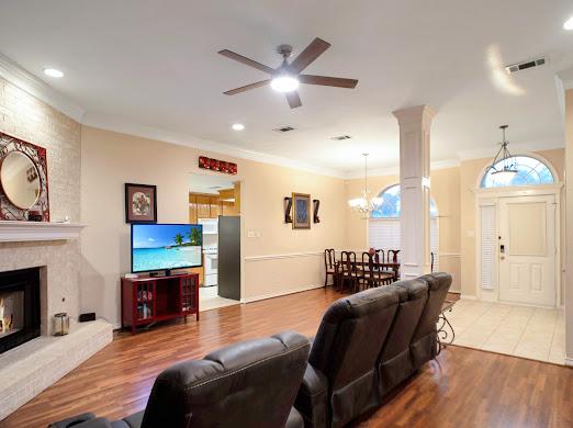 living room featuring ceiling fan with notable chandelier, a large fireplace, hardwood / wood-style flooring, and crown molding