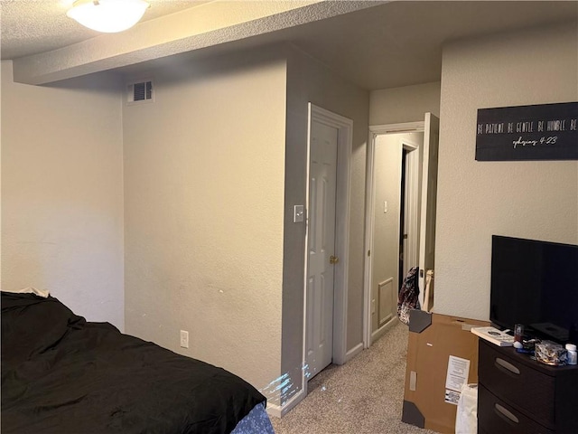 bedroom featuring light carpet and a textured ceiling