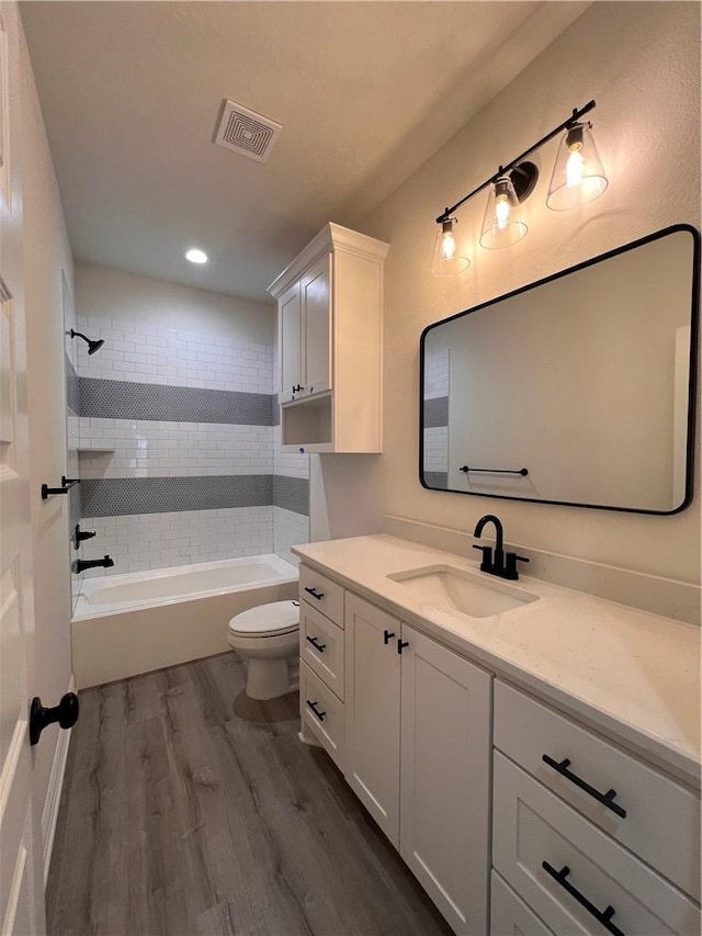 full bathroom with toilet, vanity, tiled shower / bath combo, and hardwood / wood-style flooring