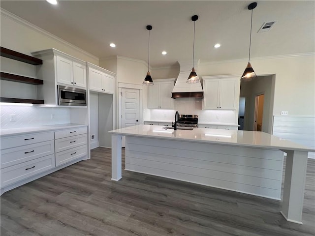 kitchen with white cabinets, custom exhaust hood, stainless steel appliances, and hardwood / wood-style floors