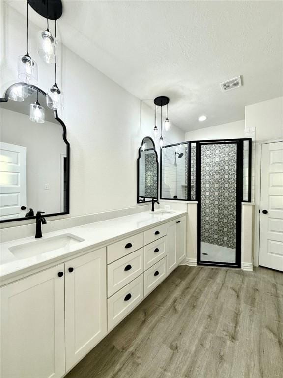 bathroom with walk in shower, vanity, a textured ceiling, and hardwood / wood-style flooring